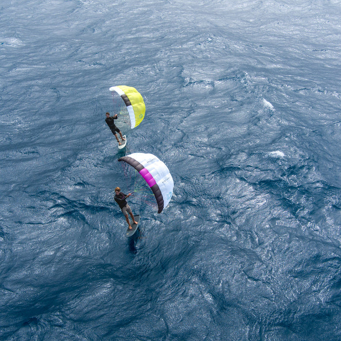 Two people kiteboarding on choppy waters with colorful duotone stash parawing