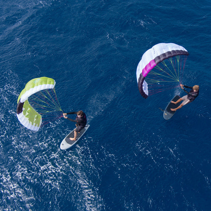 Two paragliders flying over a blue ocean with duotone stash parawing