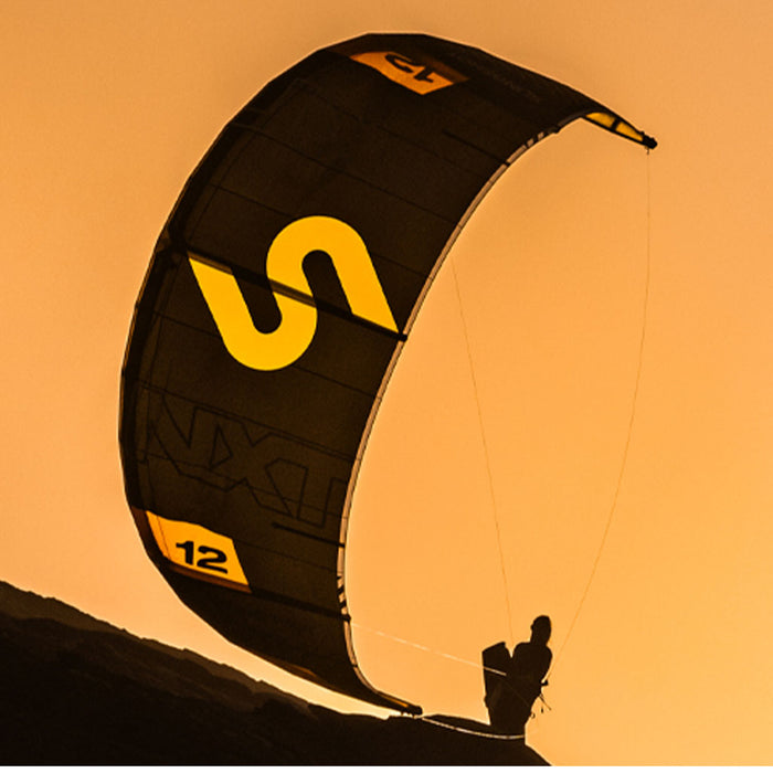 Black and yellow Code NXT v2 kite with a silhouette of a person against an orange sky
